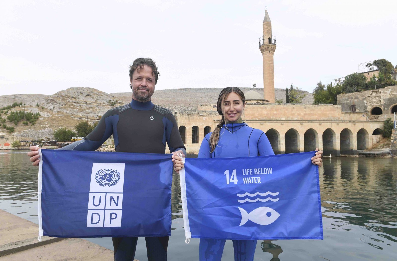 UNDP Türkiye, Suriye krizinin çevresel etkilerine yönelik olarak atık ve atık yönetimi konularında Kilis ve Şanlıurfa-Haliliye belediyeleri ile birlikte yürüttüğü proje kapsamında Dünya serbest dalış rekortmeni ve UNDP ‘Sudaki Yaşam Savunucusu’ Şahika Ercümen ile Halfeti’de Sıfır Atık Dalışı gerçekleştirdi. Birleşmiş Milletler Kalkınma Programı (UNDP) Türkiye Ülke Ofisi, rekortmen sporcu Şahika Ercümen ve basın mensuplarının katılımıyla Şanlıurfa’da sürdürülebilir kalkınma ve sosyo-ekonomik gelişmeye yönelik çeşitli UNDP projelerini ziyaret etti. Şanlıurfa’nın Haliliye ilçesi ve Kilis’te yürütülen “Sıfır Atık” projesi kapsamında gerçekleşen ziyaretler sonrası Ercümen, Halfeti’de, UNDP Türkiye Mukim Temsilcisi Claudio Tomasi ile birlikte atık, kirlilik ve sürdürülebilirlik konularına dikkat çekmek için bir dalış gerçekleştirdi. Halfeti’de gerçekleştirilen “Sıfır Atık Dalışı” öncesinde düzenlenen etkinlik ve basın toplantısına; Şanlıurfa Vali Yardımcısı Metin Esen, Halfeti Kaymakamı Selami Korkutata, Halfeti Belediye Başkanı Şeref Albayrak, Haliliye Belediye Başkanı Mehmet Canpolat ve Kilis Belediye Başkanı Servet Ramazan’ın yanı sıra, UNDP Türkiye Mukim Temsilcisi Claudio Tomasi ve UNDP Türkiye’nin “Sudaki Yaşam Savunucusu” Şahika Ercümen de katılarak sürdürülebilir kalkınma gündemi, çevre kirliliği, atık ve UNDP’nin Suriye krizinin çevresel etkilerine yönelik projeleri konularında açıklamalarda bulundu. “Ev Sahibi Topluluklar İçin Etkin Kentsel Atık Yönetimi, Faz 2: Katılımcı Atık Yönetimi Aracılığı İle Sosyal Uyumun Güçlendirilmesi” projesi kapsamında gerçekleştirilen etkinlik, Kilis ve Haliliye’nin atık sorununa yönelik sürdürülebilir çözümlere ve sosyal uyum konusuna dikkat çekmeyi amaçladı. Sıfır Atık Projesi önemli çünkü “Gezegenimiz, aslında bizim evimiz. Ve başka bir evimiz yok” Etkinliğin açılış konuşmasını gerçekleştiren UNDP Türkiye Mukim Temsilcisi Claudio Tomasi, “Nüfus hareketleri, göç, artan kirlilik, çevresel kaygılar ve iklim değişikliği giderek daha fazla bağlantılı hale geliyor. Kilis ve Şanlıurfa’da ani nüfus artışı ile birlikte UNDP’nin krizlere müdahale yaklaşımı, gelişen, büyüyen ve mültecileri ağırlayan şehirlerin acil ihtiyaçlarına, uzun vadeli ve sürdürülebilir çözümler sunmayı hedefliyor. Çevre kirliliği, ağırlaşan atık sorunu ve kentlerin altyapı gereksinmeleri, bizi ve belediyeleri krizin çevresel etkileri üzerinde birlikte çalışmaya yönlendirdi” dedi. Çevresel sürdürülebilirliğin sağlanmaması durumunda, ekonomik sürdürülebilirliğin de sağlanamayacağını dile getiren Tomasi, “UNDP olarak bizim amacımız, sorumlu bir şekilde üreten ve sorumlu bir şekilde tüketen toplumlar oluşturabilmek. Üretimimizi gerçekleştirirken ürettiğimiz ürünlerin geri dönüşümünün yapılabilmesi gerekiyor. Atıkların en aza indirgenmesi gerekiyor. Sıfır atık toplumuna bu şekilde ulaşabileceğimizi düşünüyorum.” şeklinde konuştu. Şahika Ercümen ise, “Son yıllarda en çok karşılaştığım şey, suyun altındaki atıklar ve çöpler. Etkilenen bir doğa, artık nefes alamayacak hale geldiğimiz bir gezegen ve beraberinde ekonomimizin de bundan çok etkilendiğini görüyoruz. Geri dönüşüm imkanlarını kullanmadığımız için çok büyük ekonomik kayıplar yaşadığımız bir gidişattayız. Sudaki Yaşam Savunucusu olarak bu görevi yapmaktan çok büyük bir onur duyuyorum.” dedi. Etkinliğe katılan Kilis Belediye Başkanı Servet Ramazan ve Haliliye Belediye Başkanı Mehmet Canpolat da katı atık ve geri dönüşüm alanlarında UNDP ile birlikte yürüttükleri çalışmalar hakkında katılımcılara bilgi verdi. Konuşmaların ardından tekneyle dalış noktasına geçen heyet, Şahika Ercümen ve Claudio Tomasi’nin gerçekleştirdiği ‘Sıfır Atık Dalışı’nı takip etti. UNDP, Hatay, Kilis, Şanlıurfa ve Gaziantep’te yerel idareleri ve özellikle belediyeleri sıfır atık sistemlerinin kurulması, etkin, verimli ve sürdürülebilir atık yönetimi ve bertarafı konularında gerekli plan, strateji ve politikaların geliştirilmesi, halkın çevre ve atık konularındaki duyarlılığının artırılması yoluyla destekliyor. Çevre ve Şehircilik Bakanlığı ile UNDP tarafından yürütülen “Ev Sahibi Topluluklar için Etkin Kentsel Atık Yönetimi Faz II: Katılımcı Atık Yönetimi Aracılığı ile Sosyal Uyumun Güçlendirilmesi Projesi”, yoğun göç baskısı altındaki Kilis ve Haliliye’de atık yönetimi uygulamalarını iyileştirmeyi ve toplum temelli, katılımcı bir atık yönetim sistemi geliştirerek toplumsal uyumu da desteklemeyi amaçlıyor. Amerika Birleşik Devletleri Nüfus, Mülteciler ve Göç Yönetimi Bürosu (USBPRM) tarafından finanse edilen proje kapsamında belediyelere teknik ekipman, araç desteği, modern atık getirme merkezleri sağlanıyor. Proje sıfır atık konusunda bilinçlendirme eğitimleri, geri dönüşüm atölyeleri, geri dönüşüm konusunda mesleki eğitimler gibi aktivitelerle yerelde sıfır atık ve sürdürülebilirlik hedeflerine ulaşılması amacıyla toplum desteği oluşturmayı amaçlıyor. Ayrıca toplumu, sıfır atık hedefi doğrultusunda harekete geçirmek için çeşitli teşvik mekanizmaları oluşturuluyor. Proje kapsamında ayrıca iki kadın kooperatifinin desteklenmesi yoluyla kadınların istihdama katılımının sağlanması ve geri dönüştürülebilir atıkların ekonomiye kazandırılması için eğitimli “Geri Dönüşümcüler” yetiştirilmesi de hedefleniyor. Bilgi için: UNDP Türkiye İletişim Koordinatörü Dr. Faik Uyanık, faik.uyanik@undp.org UNDP Türkiye Suriye Portfolyosu İletişim Yöneticisi, Ruşen İnceoğlu, rusen.inceoglu@undp.org